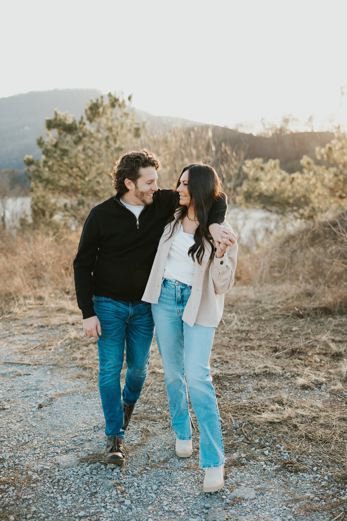 An engaged couple walking arm in arm at golden hour