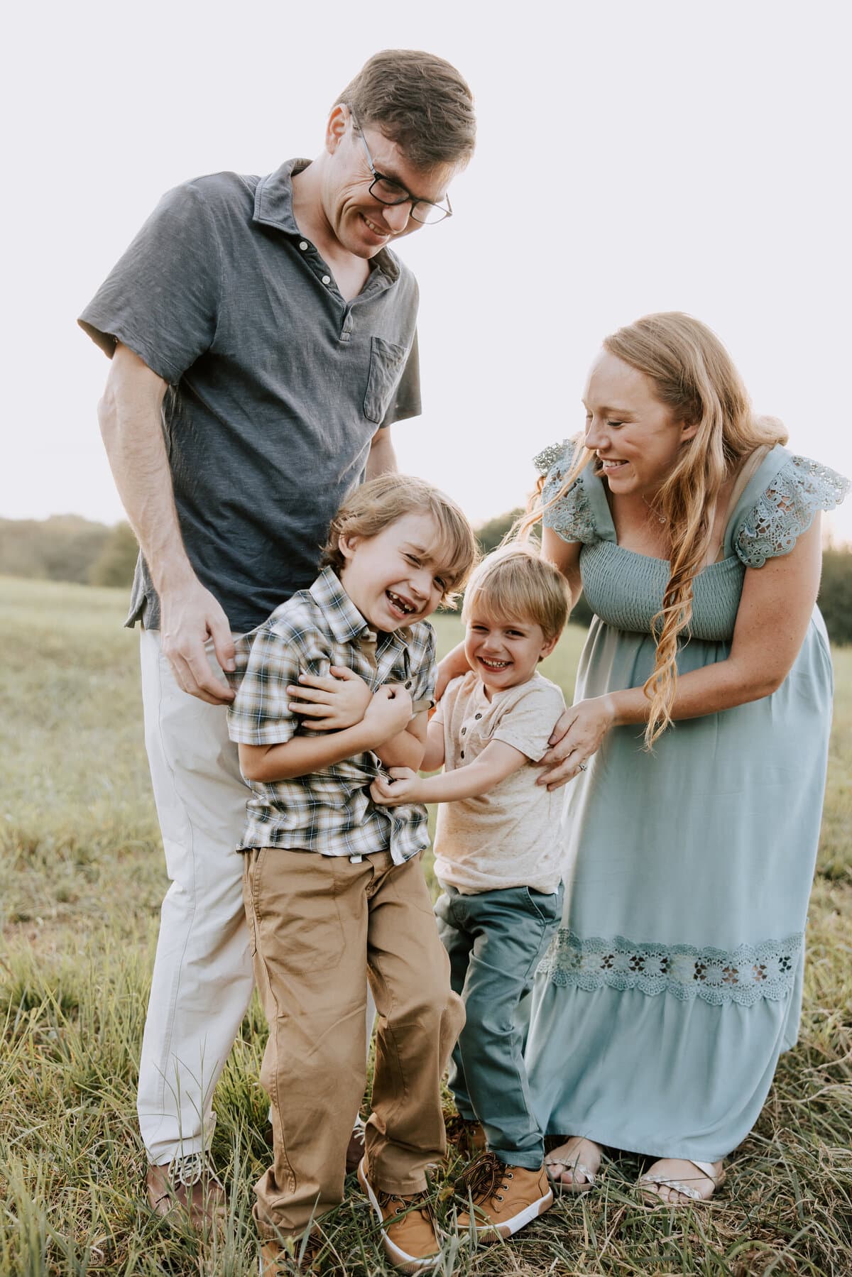 A family of four laughing together in an evening field